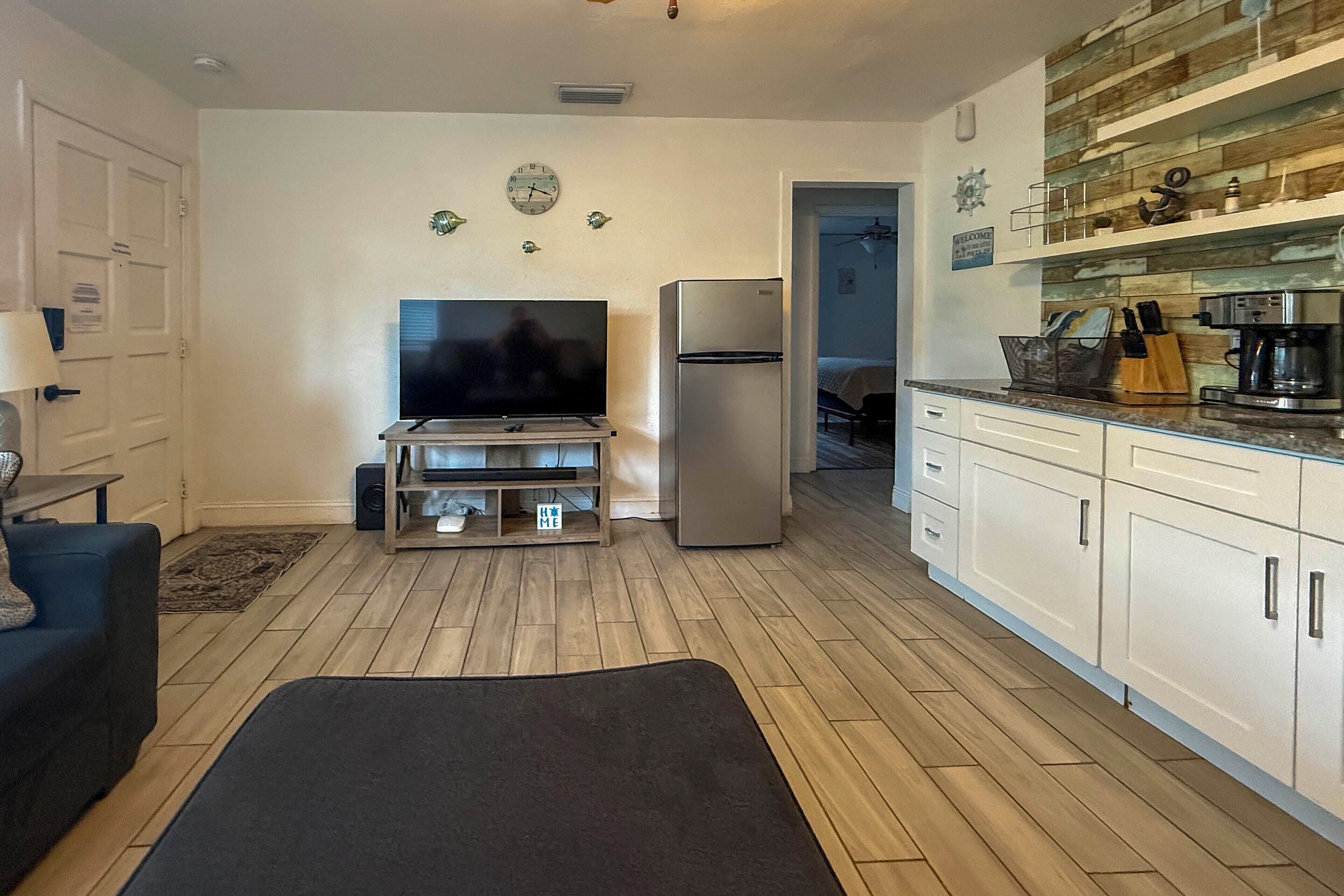 Una cocina moderna con una televisión de pantalla plana, un refrigerador y una cafetera.