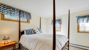 A bedroom with a four-poster bed, checkered curtains, and a bedside table with a lamp. - Winhall Home w/ Deck + Views, 6 Mi to Ski Slopes! (Bondville)