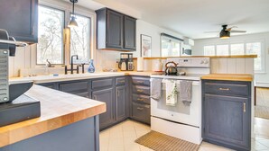 Une cuisine moderne avec des meubles de couleur sombre, une cuisinière blanche et un plan de travail en bois.