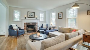 Un salon avec une cheminée, un canapé, un fauteuil et une table basse.