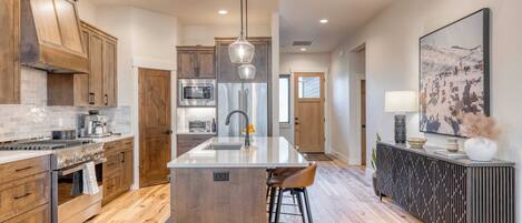 A modern kitchen with wooden cabinets, a central island, and a dining area with bar stools.