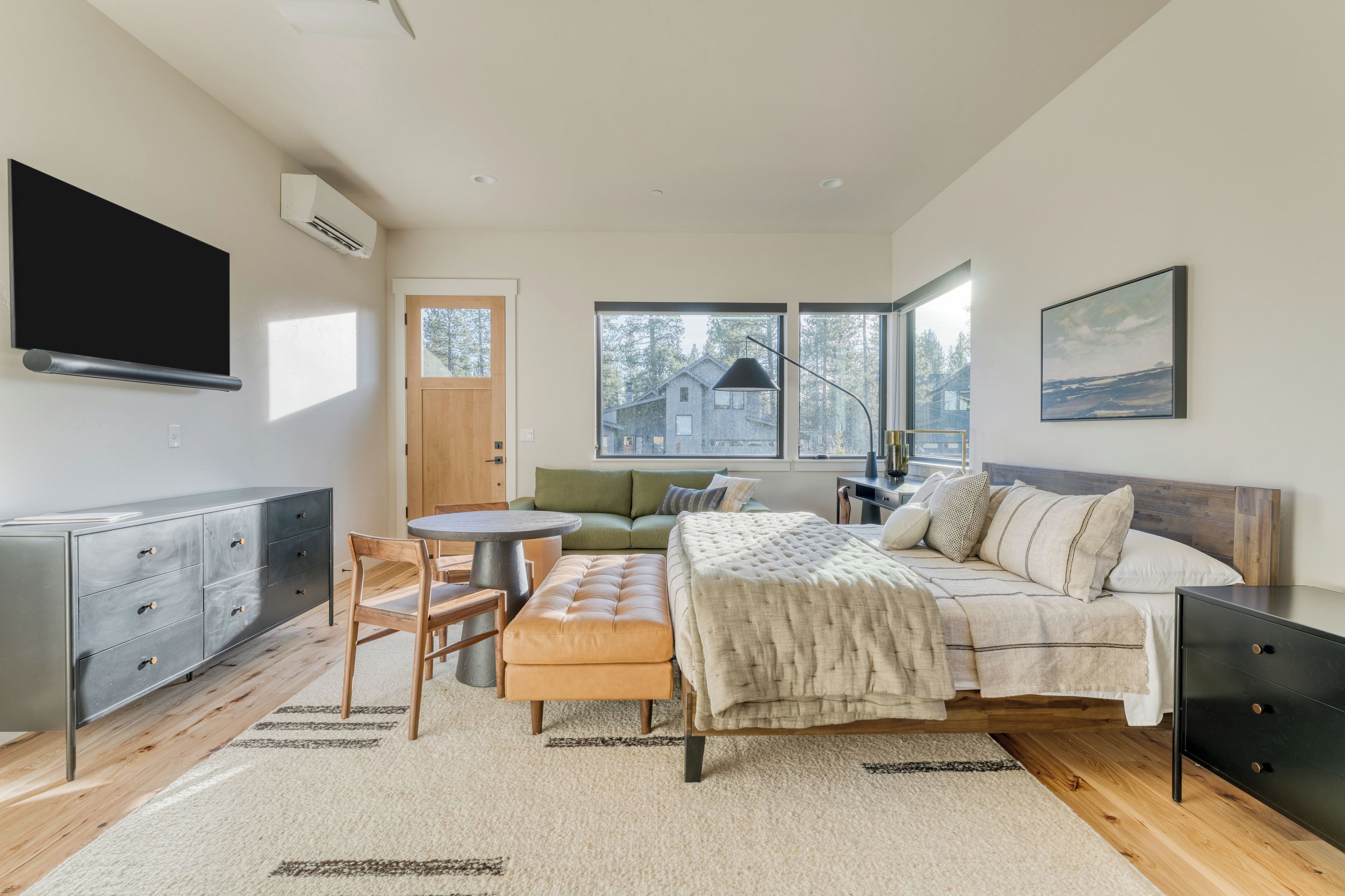 A modern bedroom with a bed, a desk, a chair, a sofa, and a TV.