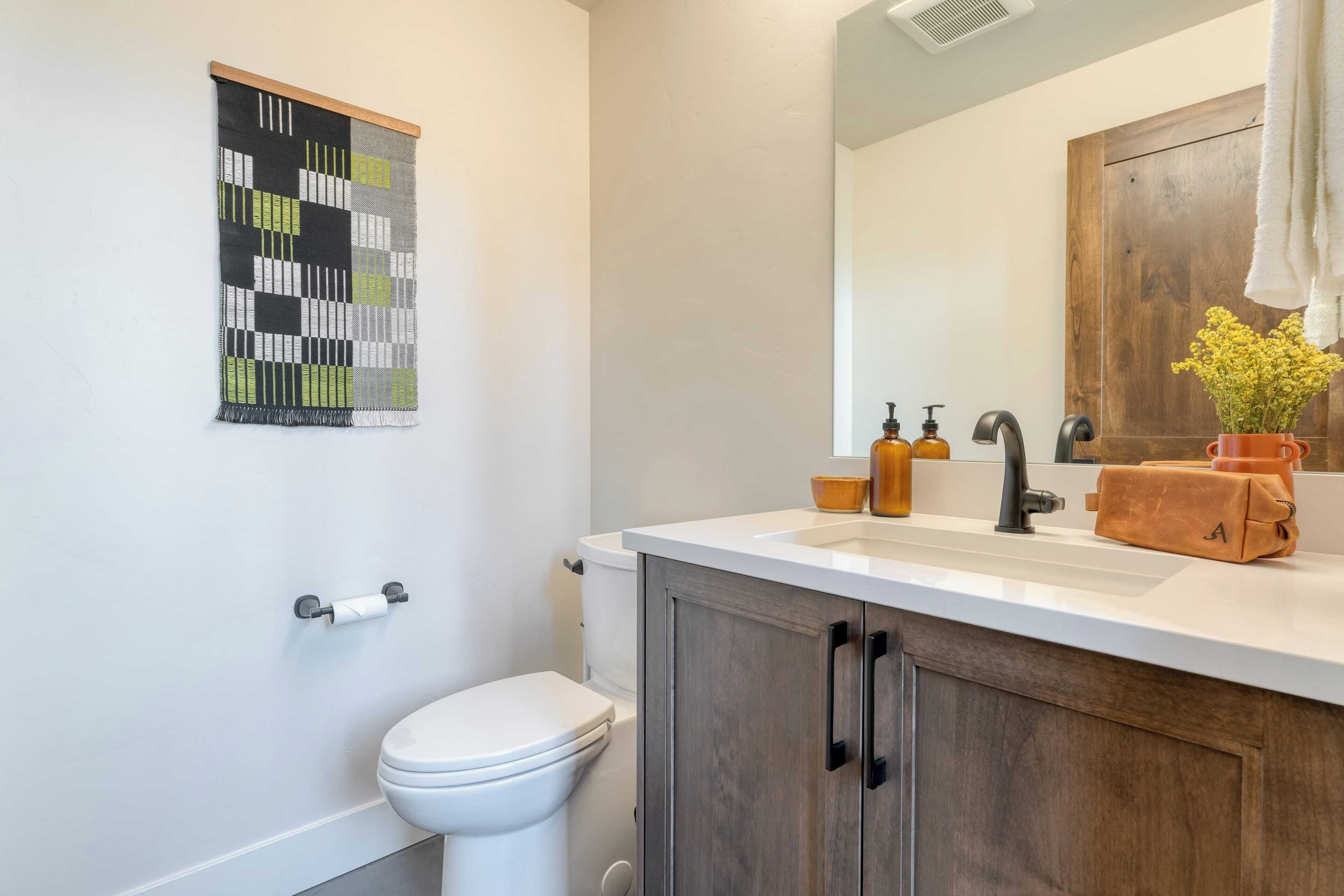 Un baño con inodoro, lavamanos con espejo y un armario de madera.