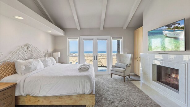 A bedroom with a bed, a chair, a fireplace, and a TV. - Beach Break by Avantstay Oceanfront, View, Patio (Newport Beach)