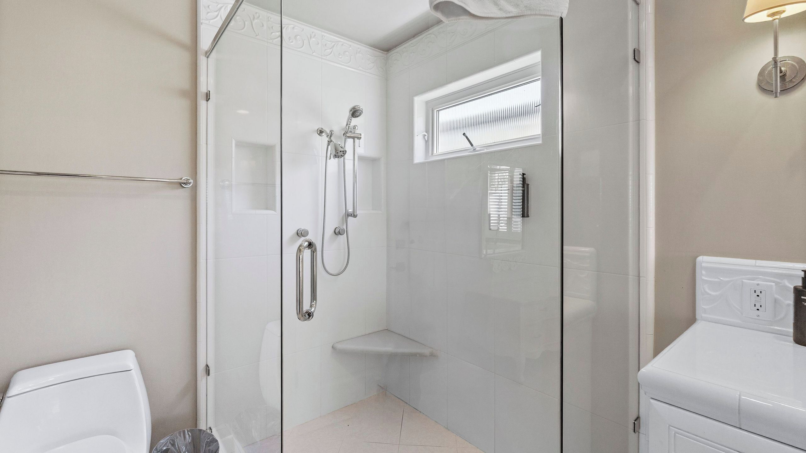 A modern bathroom with a glass-enclosed shower, a toilet, and a sink.