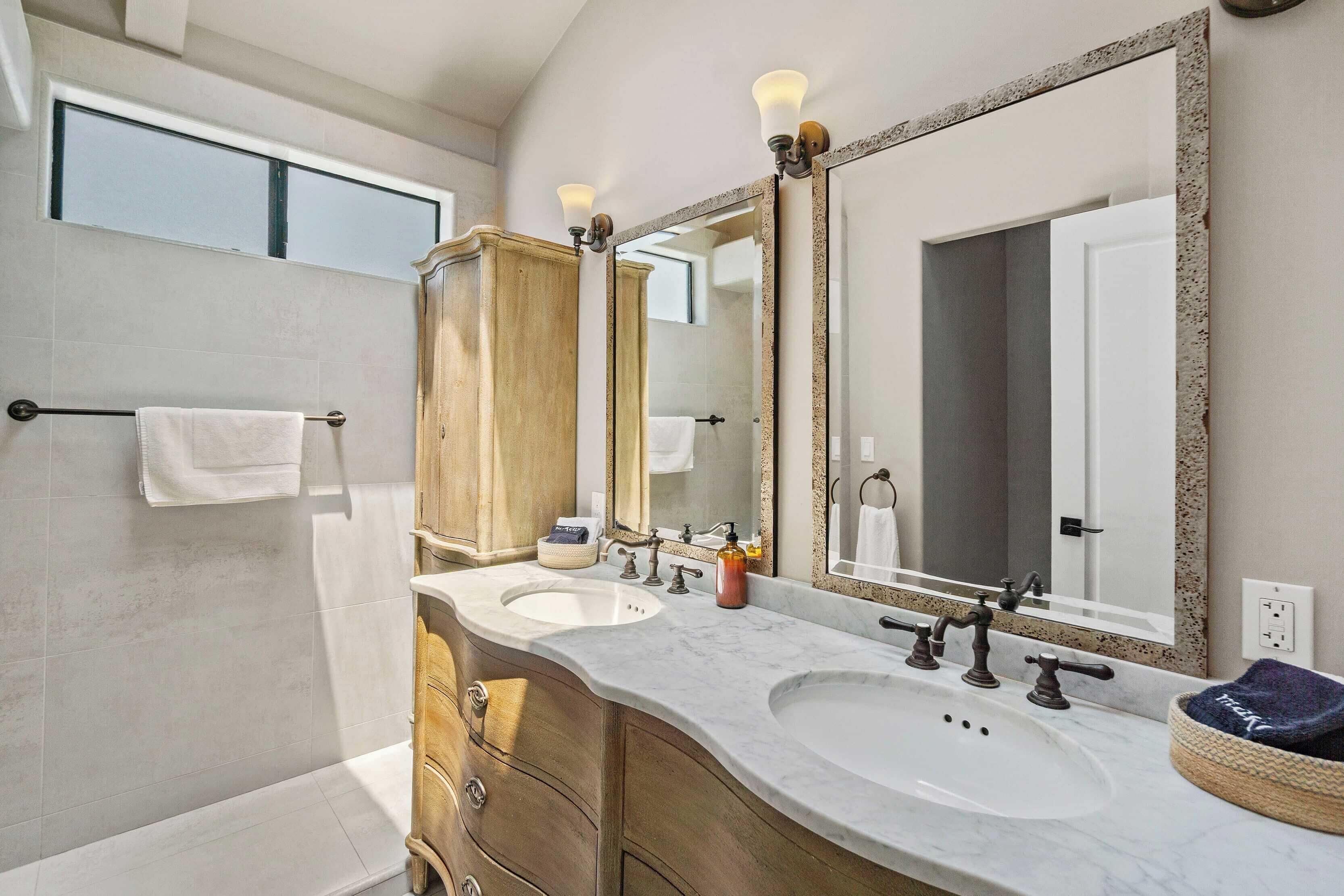 A bathroom with two sinks, a large mirror, and a towel rack.