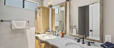 A bathroom with two sinks, a large mirror, and a towel rack.