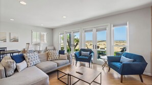 A spacious living room with a large sofa, two armchairs, a coffee table, and a view of the beach. - Beach Break by Avantstay Oceanfront, View, Patio (Newport Beach)