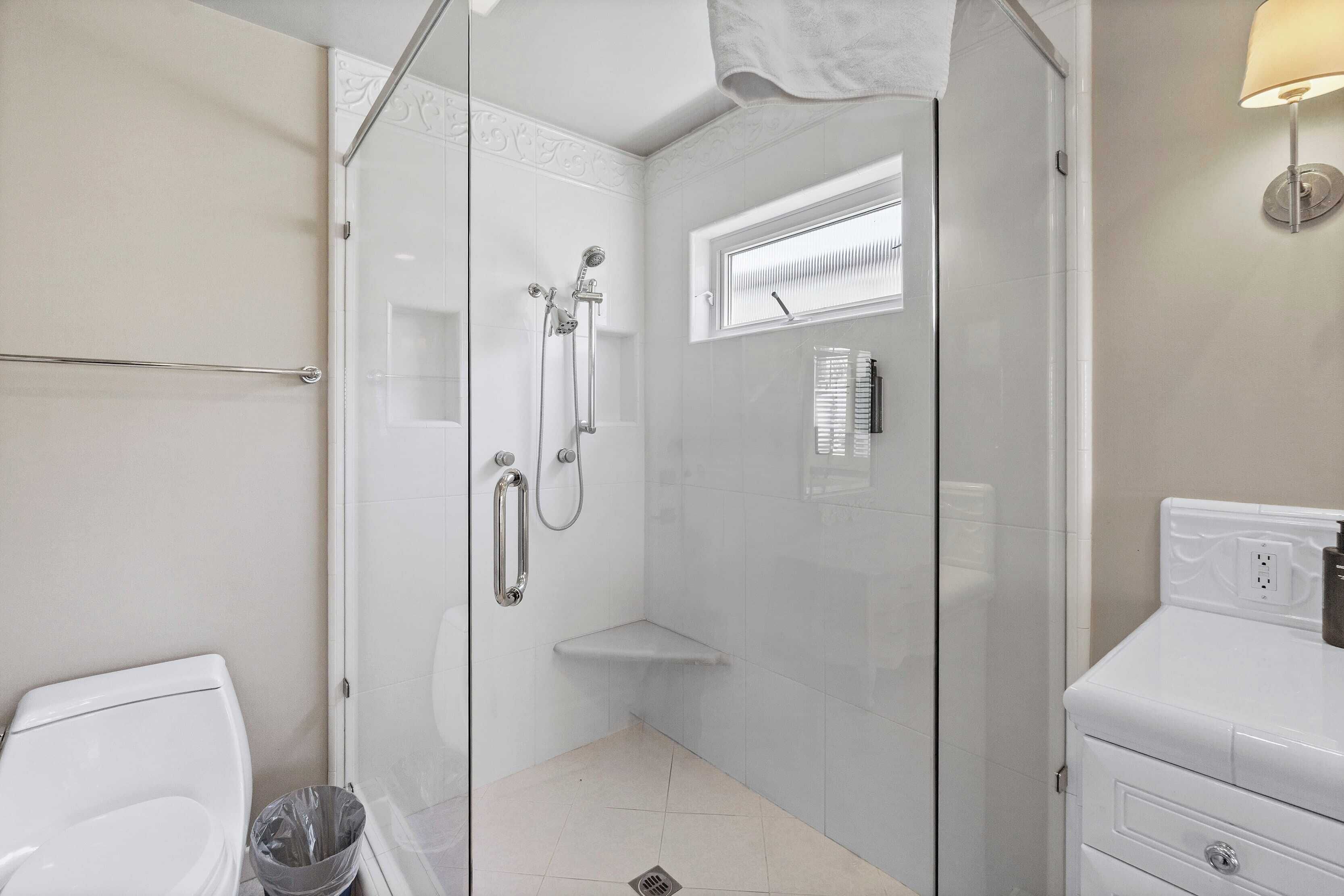Une salle de bain moderne avec une douche à parois de verre, des toilettes et un meuble-lavabo avec un miroir.