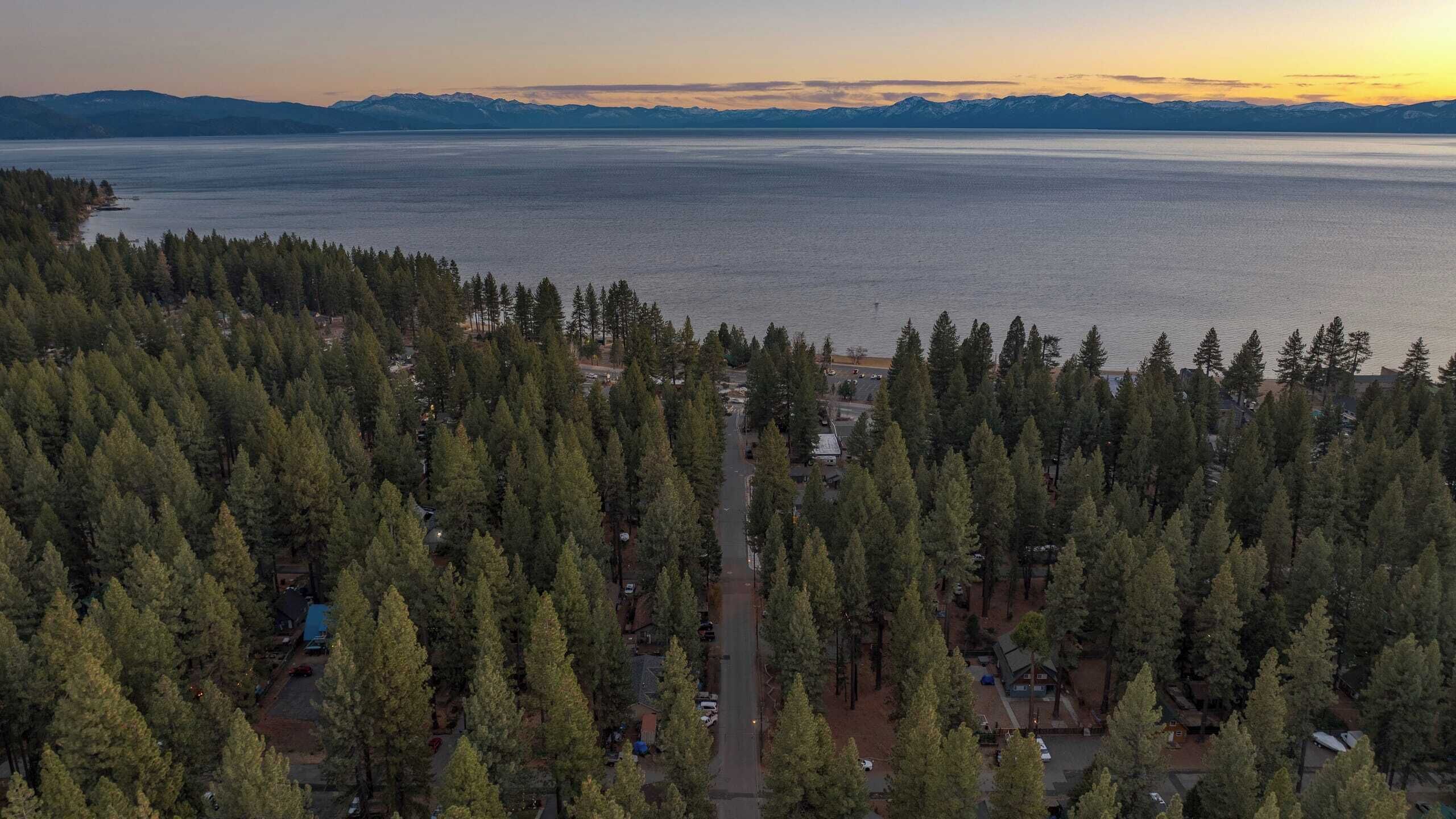 An aerial view of a forested area with a road leading to a small settlement.