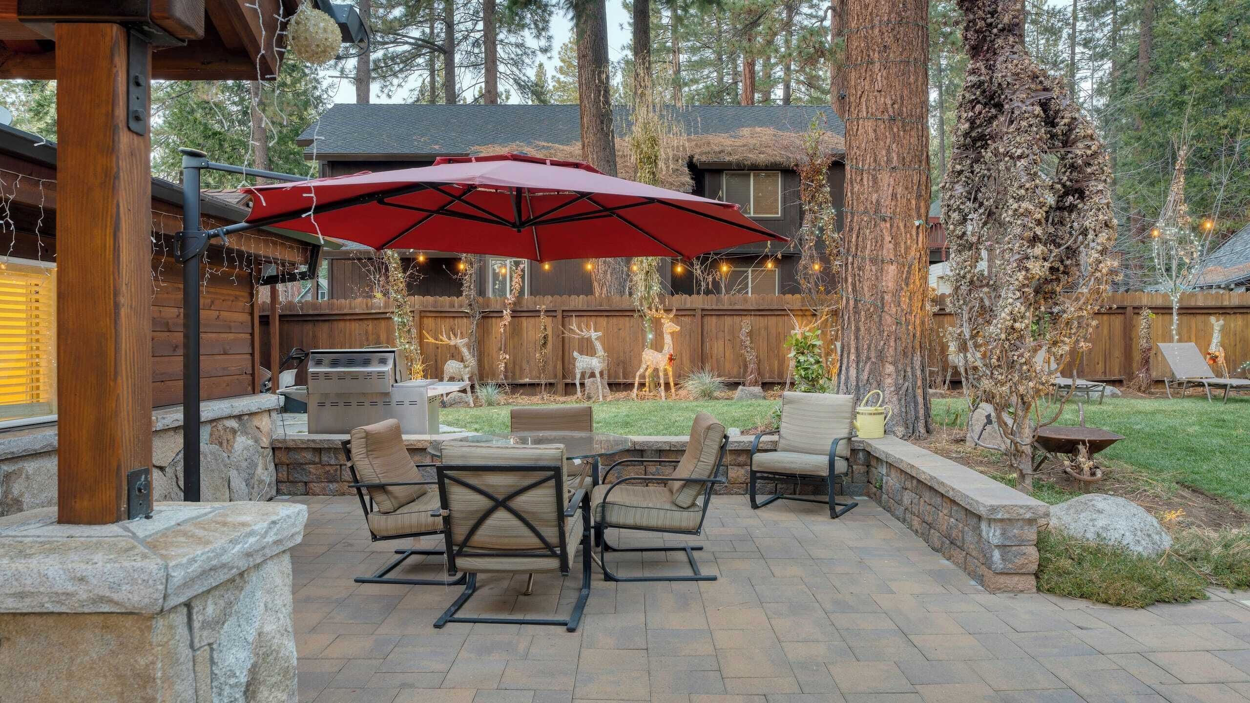 A patio area with outdoor furniture, a grill, and a red umbrella.