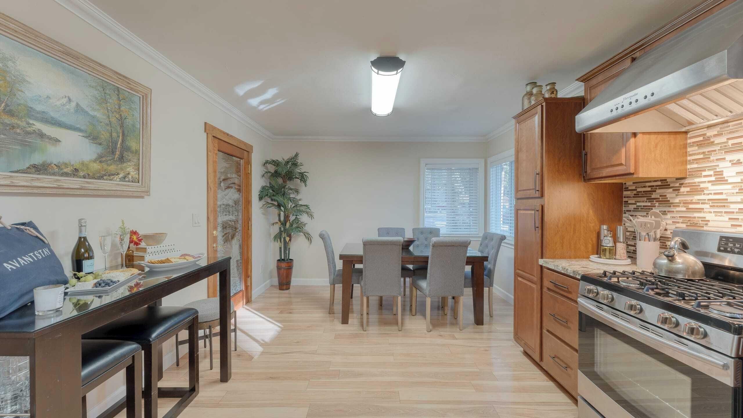 Una cocina moderna con un horno grande, armarios de madera y una zona de comedor con mesa y sillas.