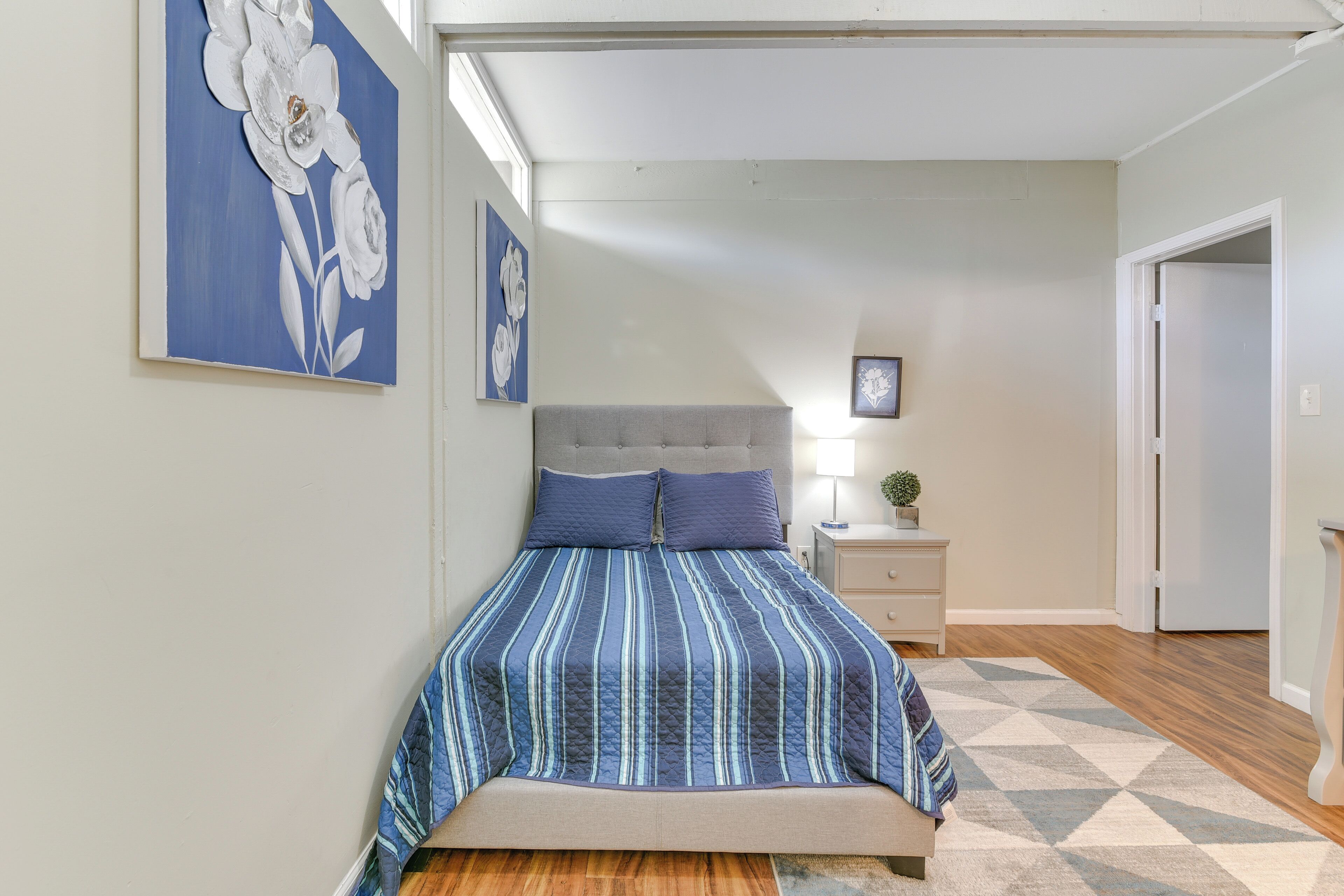 A bedroom with a bed, a nightstand, a lamp, and artwork on the walls.