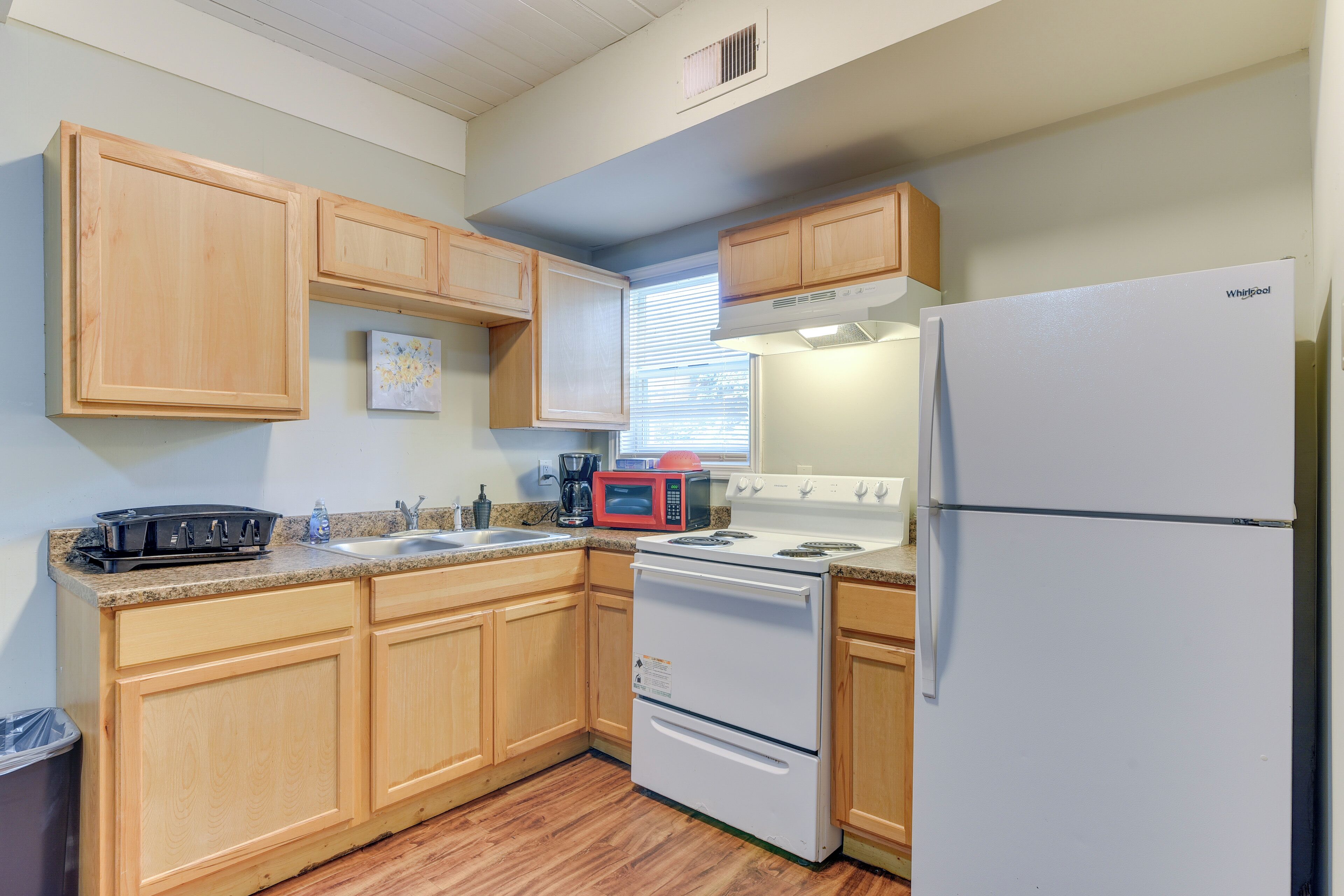A kitchen with wooden cabinets, a white refrigerator, a stove, and a microwave.