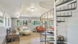 A spacious living area with a wooden floor, a spiral staircase, and large windows offering a view of the outdoors. - 4bdmountain Getawaydog Friendlyminutes to Pikes Peak & Nature (Woodland Park)