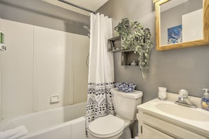 A bathroom with a bathtub, toilet, sink, and a shower curtain.