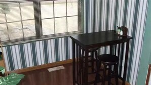 A room with a wooden floor, a dark wooden table with two chairs, and a window with blinds. - Vacation rental home Lexington (Lexington)