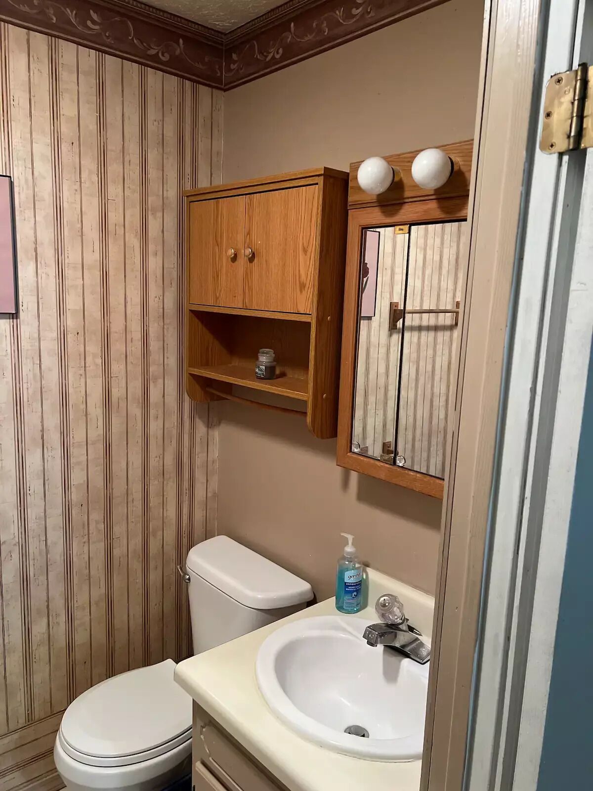 A small bathroom with a wooden vanity, a toilet, and a sink.