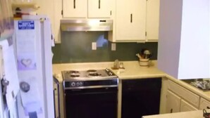 A compact kitchen with white cabinets, a stove, and a dishwasher. - Vacation rental home Lexington (Lexington)