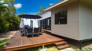 A deck with outdoor furniture and a covered area, adjacent to a building with large windows.