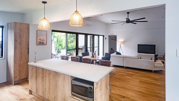 A modern kitchen with a wooden island, pendant lights, and a built-in microwave.