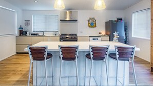 A modern kitchen with a central island, stainless steel appliances, and a large window.