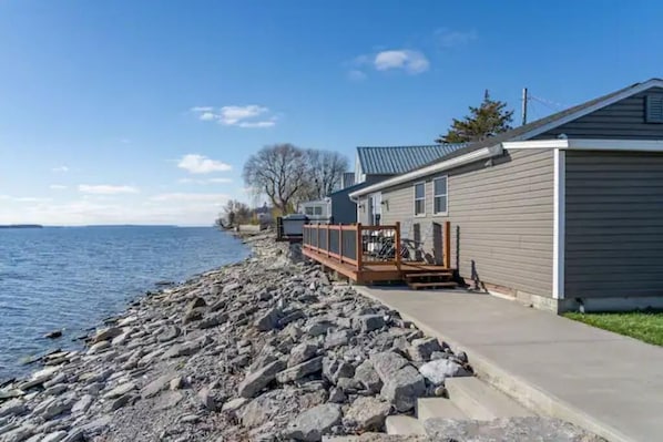 A waterfront property with a dock, a concrete walkway, and a house with a grey exterior.