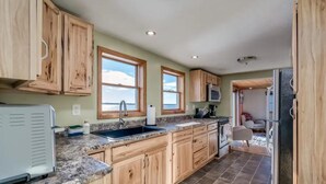 A kitchen with wooden cabinets, a granite countertop, a sink, a microwave, and a refrigerator. - Black Bay Chalet- Lake front home with magnificent views (Dexter)