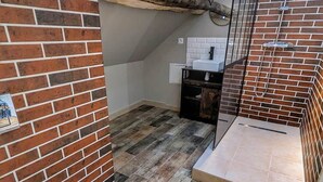 Ein kleines Badezimmer mit Toilette, Dusche und Waschbecken an einer Ziegelwand.