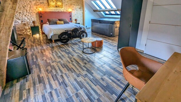 Ein Schlafzimmer im Lofts-Stil mit Steinsturz, Bett, Motorrad und Dachfenster.