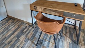 Ein modernes Zimmer mit einem Holztisch, einem Ledersessel und einem an der Wand befestigten Fernseher.