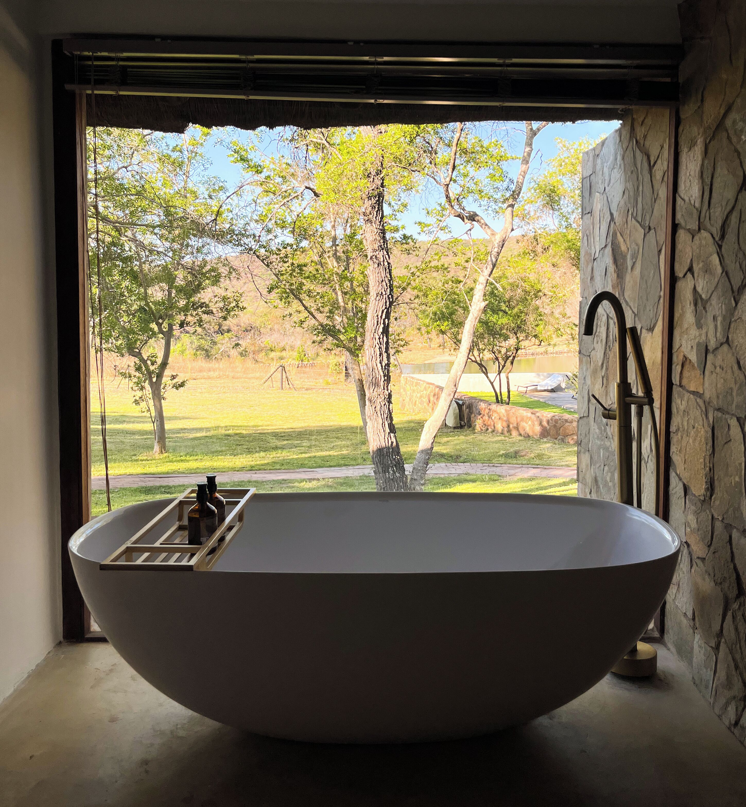 A large, freestanding bathtub in a bathroom with a view of a natural landscape.