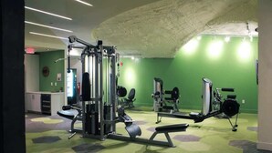 Une salle de sport équipée de divers appareils d’exercice, avec un mur végétal et un tapis à motifs.