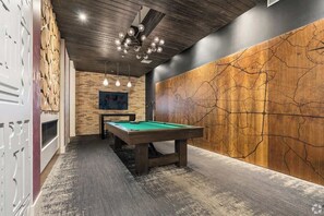 A billiards table in a room with a wooden wall and a ceiling with a unique light fixture.