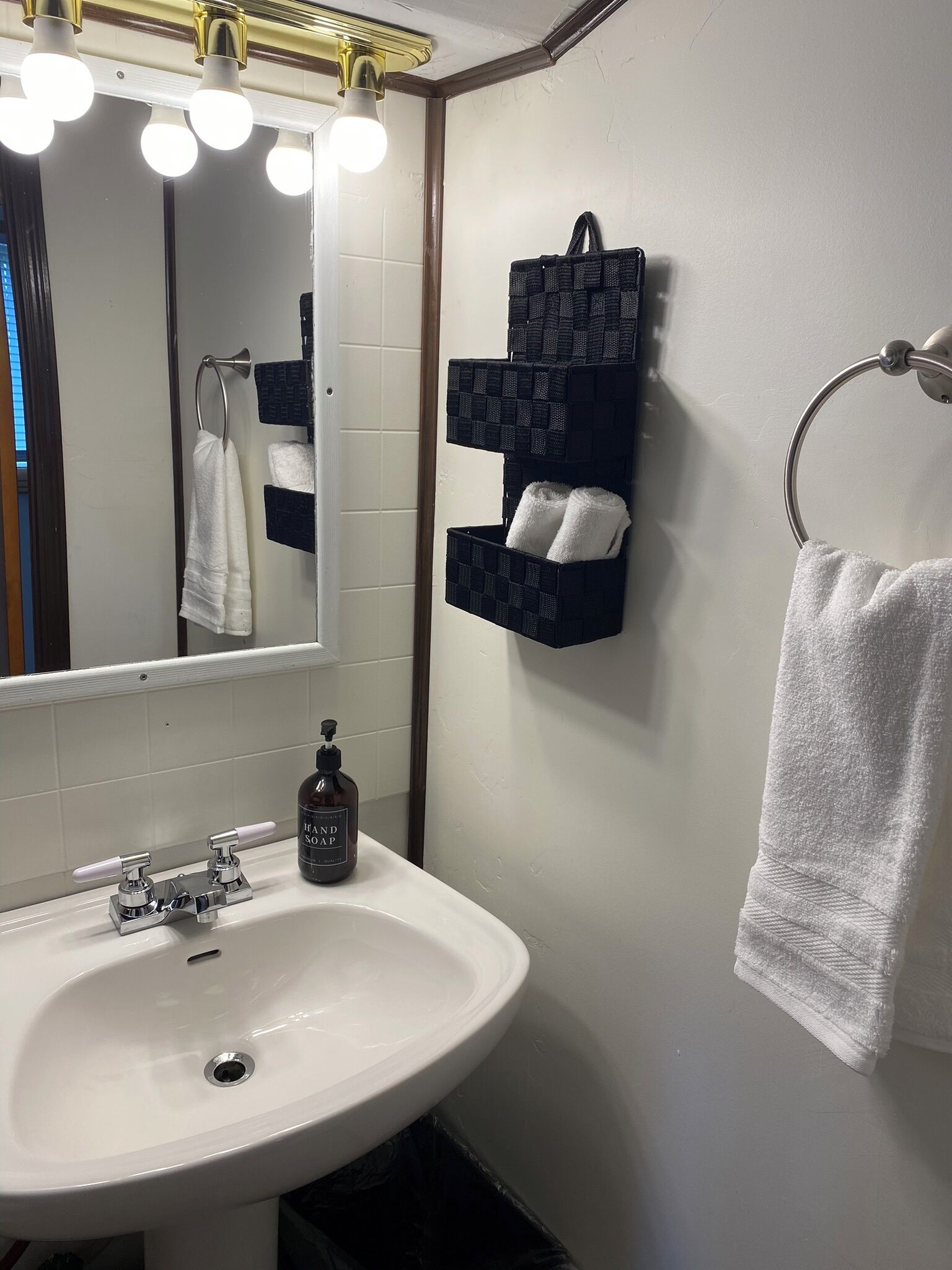 A bathroom with a white sink, a mirror, and a towel rack.