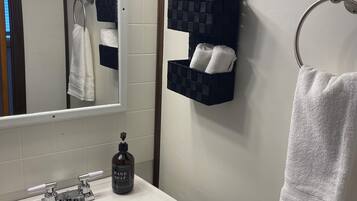 A bathroom with a white sink, a mirror, and a towel rack.