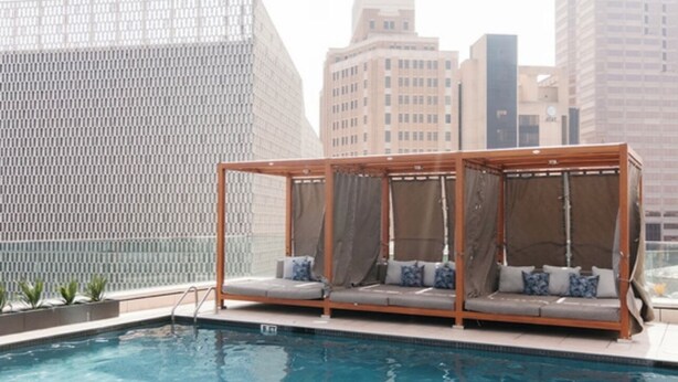 Uma área de piscina no terraço, com duas cabanas de madeira, vista para a cidade e piscina.