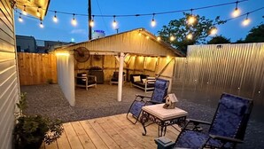 Um deck de madeira com móveis de exterior e luzes de corda.