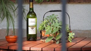 Een fles wijn, een klein schaaltje en een potplant op een houten tafel.