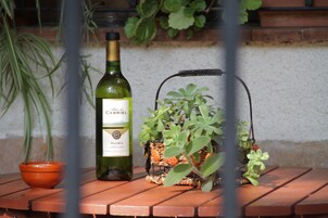 Una botella de vino, un cuenco pequeño y una planta en maceta sobre una mesa de madera.
