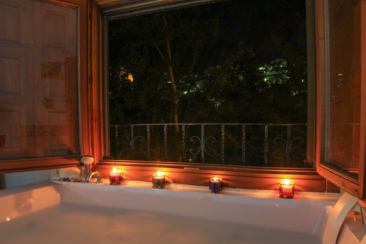 Una bañera grande con velas en una habitación con poca luz.