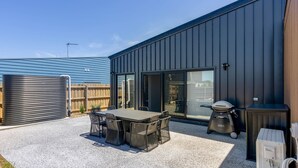 A modern patio area with a table and chairs, a grill, and a water heater.