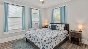 A bedroom with a bed, two bedside tables, a ceiling fan, and a window with blinds.