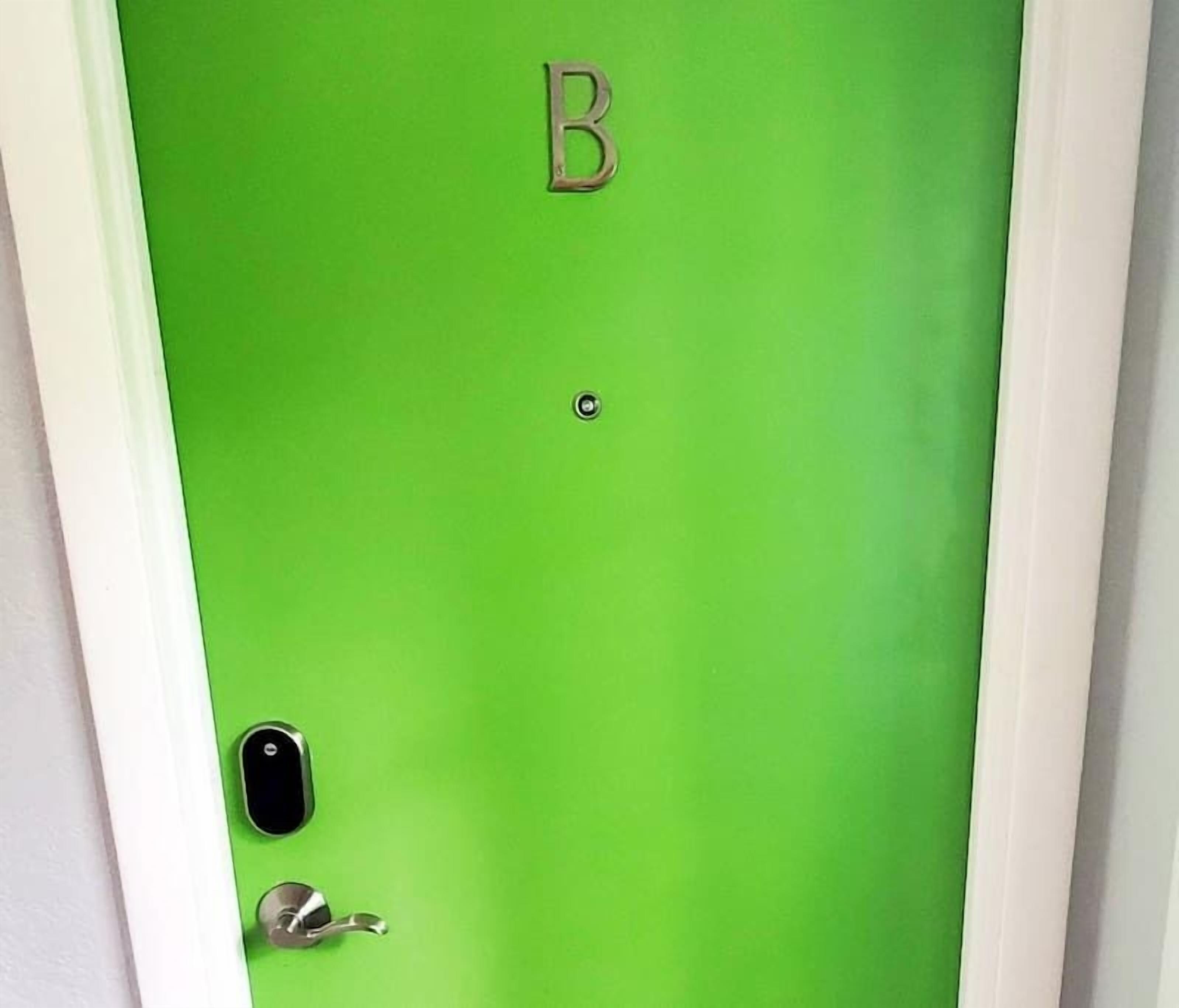 A door with a green surface, a letter 'B' above it, a peephole, and a door handle.