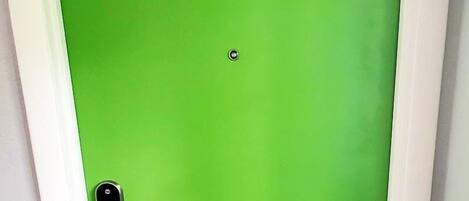 A door with a green surface, a letter 'B' above it, a peephole, and a door handle.