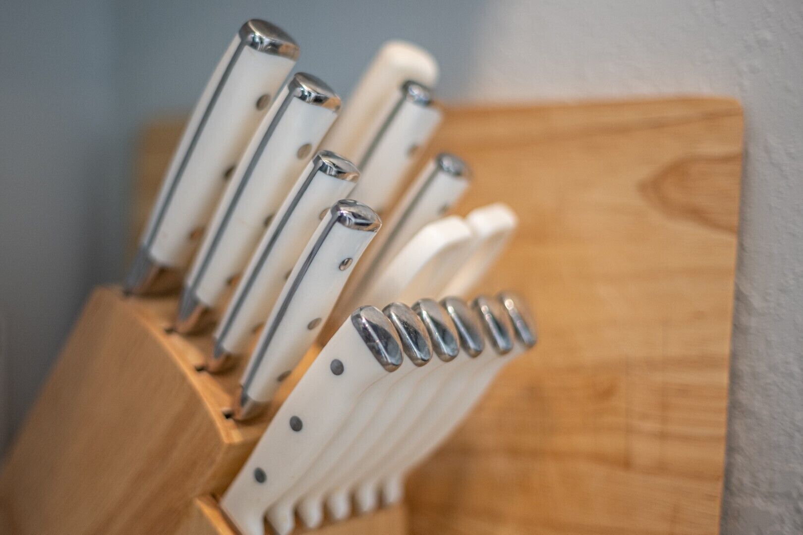 A set of knives with wooden handles and metallic blades, arranged in a wooden block.