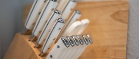 A set of knives with wooden handles and metallic blades, arranged in a wooden block.