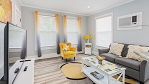 A modern living room with a sofa, a yellow armchair, a coffee table, and a television.
