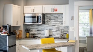 A modern kitchen with white cabinets, a stainless steel microwave, and a tiled backsplash.