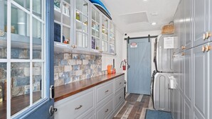 A kitchen with white cabinets, a blue door, and a tiled backsplash. - Tranquility Octopus Suite - Oceanfront Paradise! (Melbourne Beach)